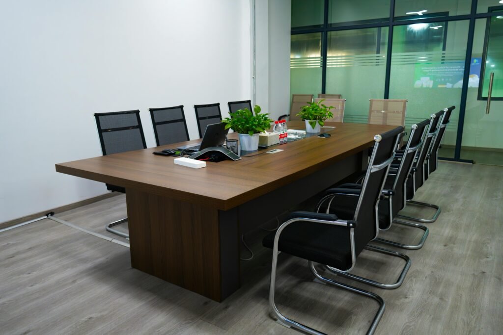 Spacious conference room featuring a long table, modern chairs, and potted plants for a professional setting.